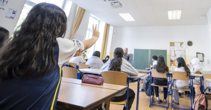 Szene aus einem österreichischen Klassenzimmer, ein Mädchen zeigt auf