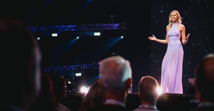 Miriam Höller steht in einem lila Kleid auf der Bühne.