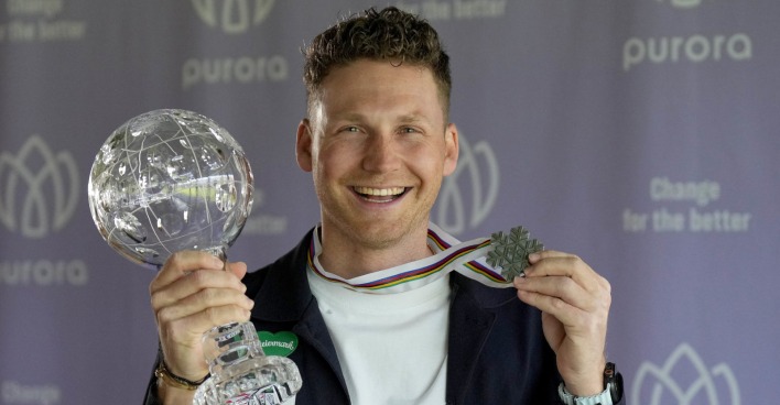 Mann hält eine Kristallkugel und eine Medaille in den Händen
