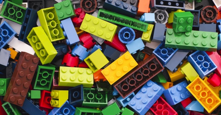 Bunte Sammlung verschiedener LEGO-Steine in unterschiedlichen Farben und Größen, chaotisch übereinander gestapelt.