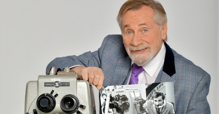 Peter Rapp zeigt stolz eine alte Aufnahme von sich mit einem historischen Fernsehgerät, das symbolisch für seine langjährige Karriere steht.