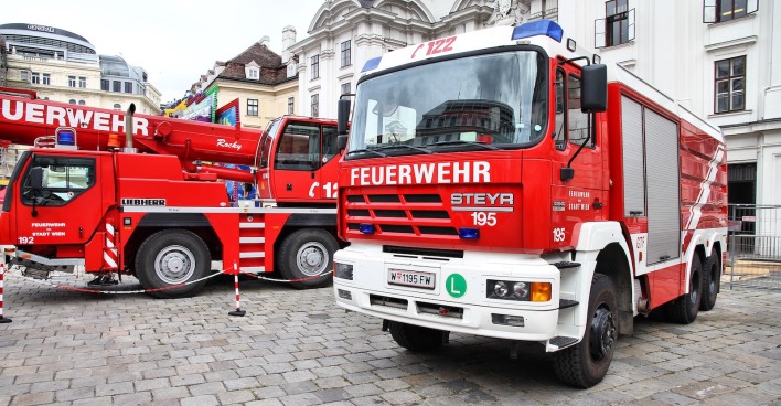 Zwei Einsatzfahrzeuge der Feuerwehr Wien stehen einsatzbereit in der Innenstadt, im Hintergrund historische Gebäude der Wiener Innenstadt.