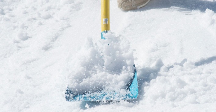 Person schaufelt Schnee mit Schneeschaufel