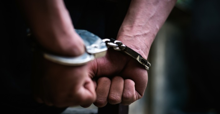 Mann trägt Handschellen hinterm Rücken