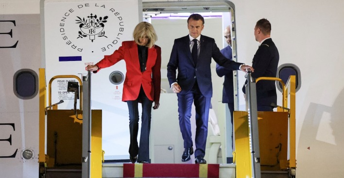 Emmanuel Macron und Brigitte Macron steigen in Hanoi gemeinsam aus dem Flugzeug. Sie trägt eine rote Jacke, er einen dunklen Anzug. Die Szene folgt unmittelbar auf den gefilmten Moment, der als mögliche Ohrfeige diskutiert wird.