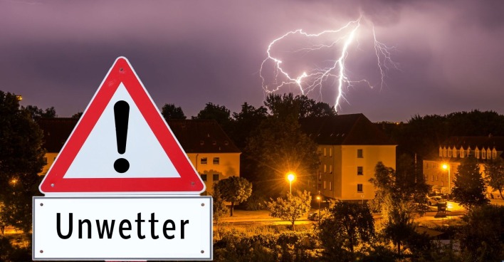 Gewitterwolke mit einem Unwetterwarnschild