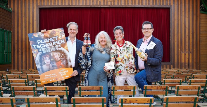 Quartett mit Revue-Plakat vor dem geschlossenen roten Vorhang der Tschauner Bühne