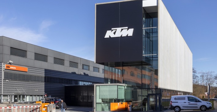 Hauptsitz der Pierer-Mobiltiy-Tochter KTM in Mattighofen mit moderner Glasfassade und großem Firmenlogo bei sonnigem Wetter