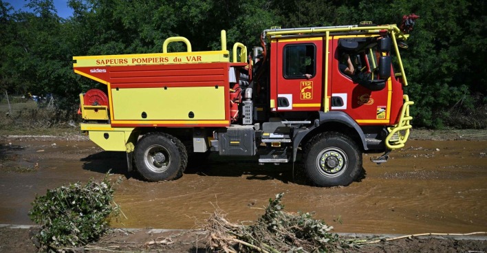 Unwetter in Südfrankreich: Ein Feuerwehrfahrzeug steht in einer überschwemmten Gegend, davor abgebrochene Baumteile