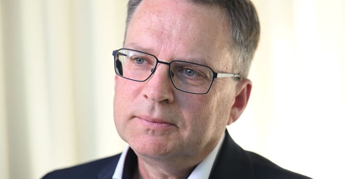 Porträt von August Wöginger, der eine Brille trägt und ernst in die Kamera blickt.