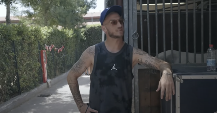 Marko Arnautović mit Sonnenbrille und blauer Kappe in einem Pferdestall, leicht lächelnd, im Hintergrund Holzstallwände und Grün.