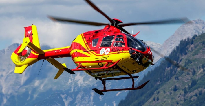 Nahaufnahme eines Rettungshubschraubers vor einer imposanten Bergkulisse