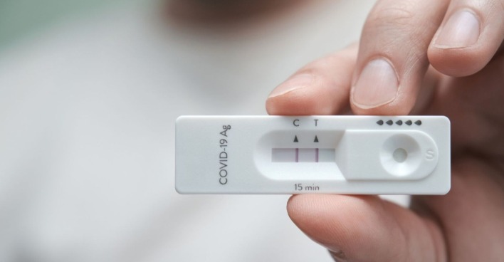Hand, die positiven Corona-Schnelltest hält