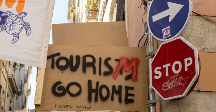 Protestplakat mit der Aufschrift „Tourists go home“ und Stoppschild in Barcelonas Altstadt