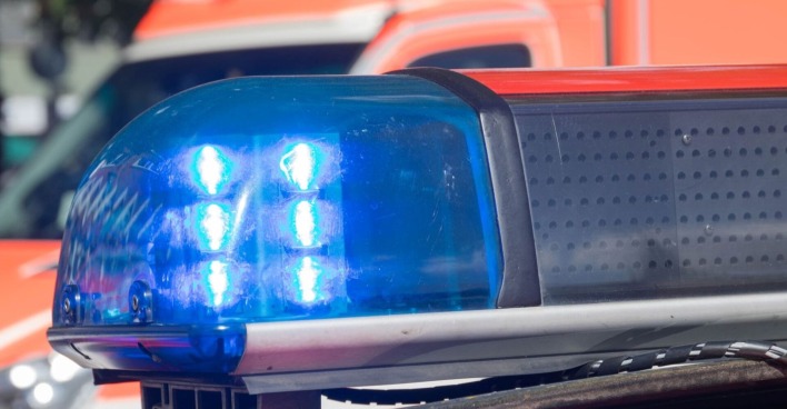 Blaulicht eines Polizeifahrzeugs im Einsatz, unscharf im Hintergrund ein Einsatzfahrzeug.