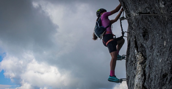 Eine Frau klettert auf einem Klettersteig.