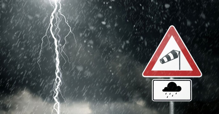 Warnschild neben einer Gewitterwolke und einem Blitz