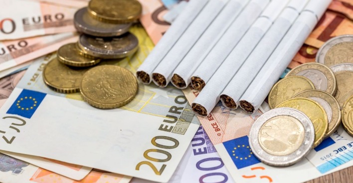 Zigaretten liegen auf Euronoten, daneben liegen Euromünzen