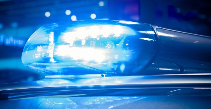 Blaulicht eines Polizeiautos in der Nacht, unscharfe Lichtreflexionen im Hintergrund.