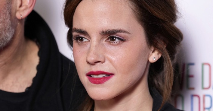 Nahaufnahme von Emma Watson mit dezentem Make-up und roten Lippen, lächelnd bei einem öffentlichen Auftritt.