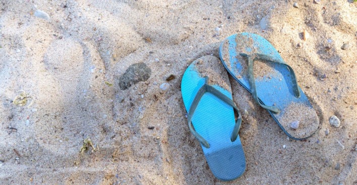blaue Flip Flops im Sand