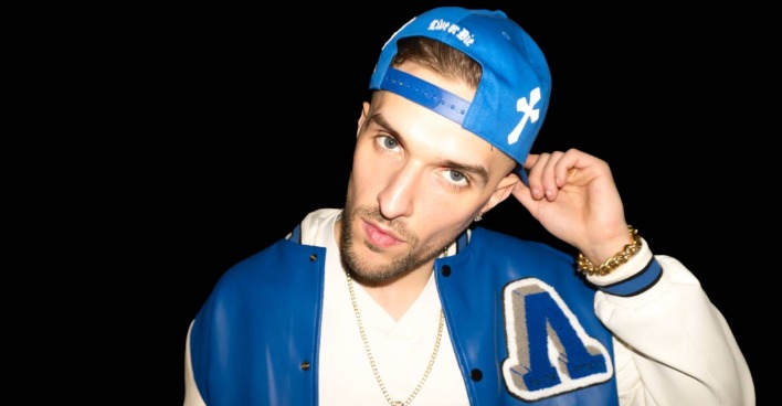 Porträt des Klagenfurter Rappers Gavis Dean, der eine blaue Baseball-Kappe sowie eine weiß-blaue Sportjacke trägt