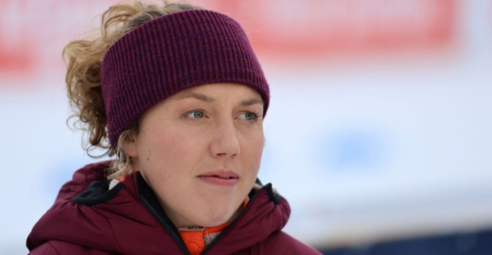 Nahaufnahme von Laura Dahlmeier mit violettem Stirnband und roter Winterjacke, aufgenommen bei einer Veranstaltung im Freien.