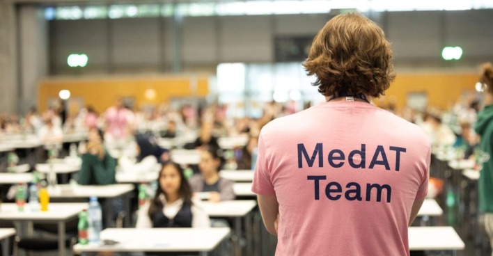 Mann steht in einem MedAT T-Shirt