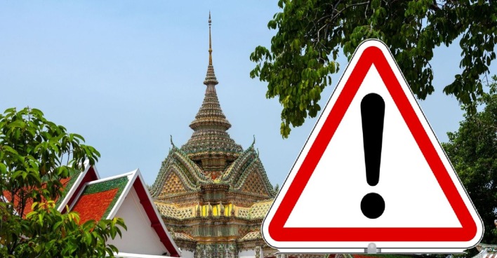 Warnschild mit Ausrufezeichen vor thailändischem Tempel – Symbolbild zur aktuellen Reisewarnung wegen des Konflikts zwischen Thailand und Kambodscha.