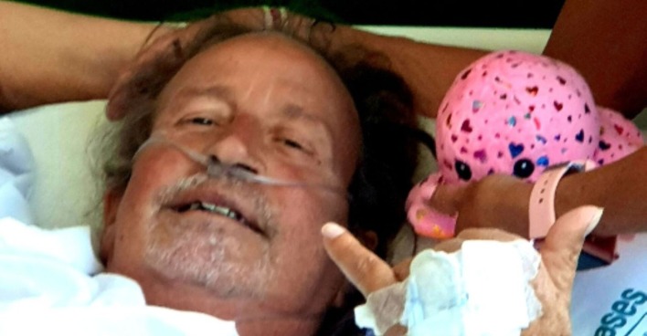 Thommy Schmelz liegt im Krankenhausbett und zeigt eine Coolness-signalisierende Handgeste