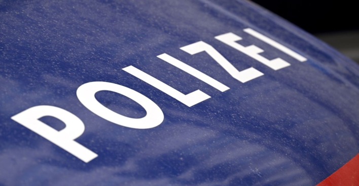 Nahaufnahme eines blauen Polizeifahrzeugs mit weißem Schriftzug „Polizei“.