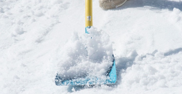 Gelb-blaue Schneeschaufel schaufelt Schnee