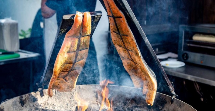 Zwei Stücke gewürzter Lachs werden traditionell als Flammlachs über offenem Feuer gegart.