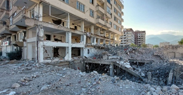 Teilweise eingestürztes mehrstöckiges Wohnhaus mit freiliegenden Stahlträgern und Trümmern im Vordergrund:  Nurdagi, Tuerkei, TUR - Zerstoerte Hochhaeuser im Erdbebengebiet Region Gaziantep