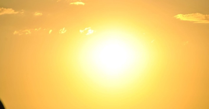 Grell strahlende Sonne am wolkenarmen Himmel, die intensive Hitze und sonniges Wetter andeutet.