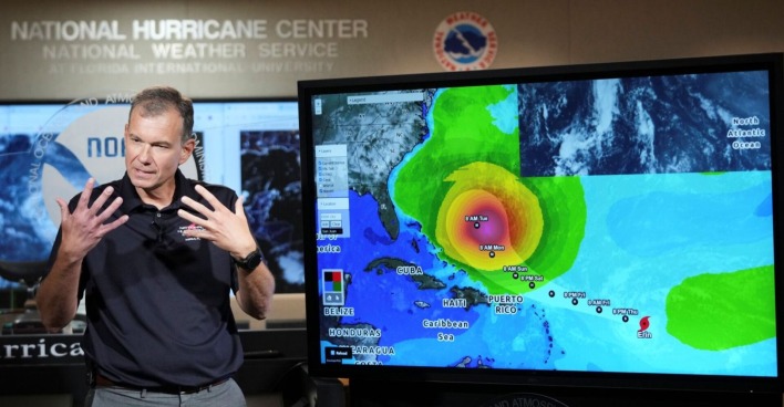 Meteorologe steht vor einer digitalen Wetterkarte mit der prognostizierten Zugbahn von Hurrikan Erin, der sich über der Karibik befindet und in Richtung Südostküste der USA zieht.