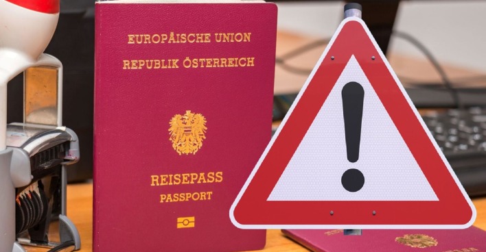 Zwei österreichische Reisepässe auf einem Schreibtisch neben einem Stempelgerät und einer Computertastatur, ein großes Warnschild.