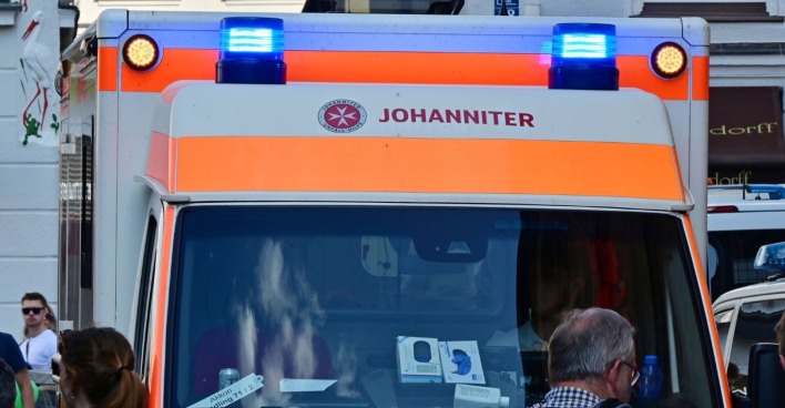 Rettungsfahrzeug der Johanniter mit eingeschaltetem Blaulicht in der Münchner Innenstadt