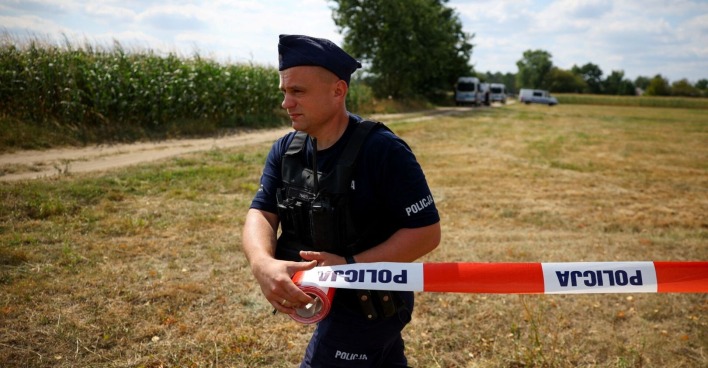 Polnischer Polizist mit Absperrband sichert ein Feld bei Osiny nach dem Absturz einer russischen Drohne.