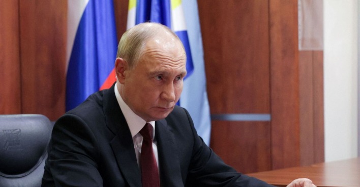 Russlands Präsident Wladimir Putin bei einer offiziellen Ansprache in Moskau, vor russischer Flagge und im Anzug