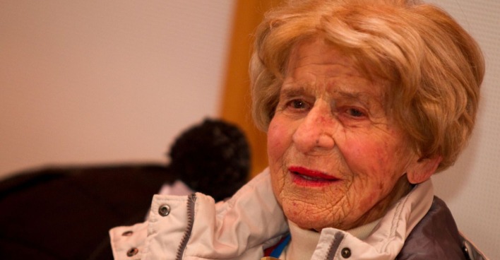 Porträt der betagten Anneliese Schuh-Proxauf mit hellbraunem Haar und Winterjacke, aufgenommen in einem Innenraum.
