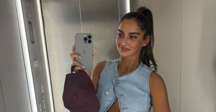 Tanja Makaric posiert in einem Aufzug und zeigt ihren Babybauch, in der Hand hält sie eine Kappe