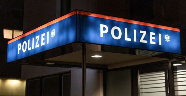 Leuchtendes Schild vor einer Polizeiwache in der Nacht.