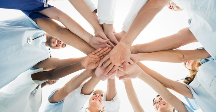 Gruppe von Menschen im Kreis, die sich an den Händen halten | Credit: iStock.com/Andrey Popov