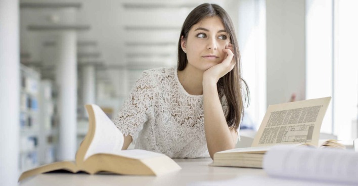 Nachdenkliches Mädchen sitzend vor einem Schreibtisch