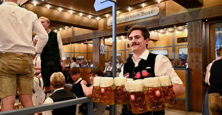 Kellner auf dem Münchner Oktoberfest trägt Maßkrüge