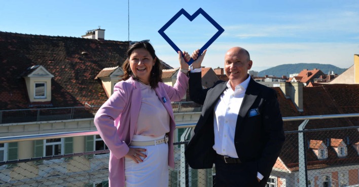 Eine Frau und ein Mann auf einer Terrasse über einer Stadt