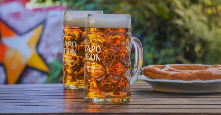 Zwei Maßkrüge mit Bier und Brezn am Holztisch