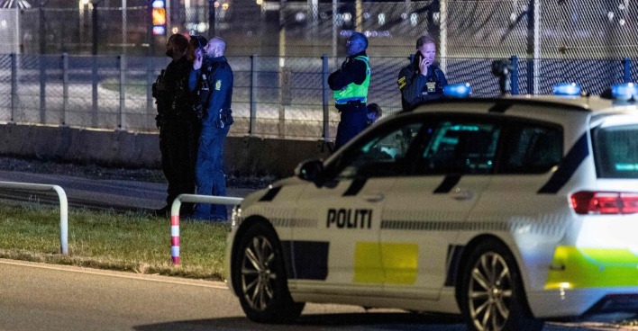 Mehrere Polizisten und ein Einsatzfahrzeug der dänischen Polizei vor einem abgesperrten Bereich am Flughafen Kopenhagen in der Nacht.