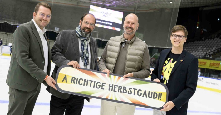 Vier Männer halten gemeinsam ein Schild hoch